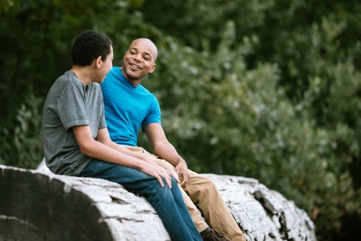 Father and son talking outside on a log about KET+ Ketamine Treament at Andala Health in San Antonio, Texas.