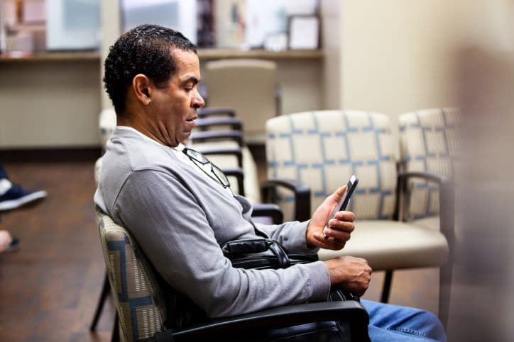 Man-Sitting-in-Chair-Looking-at-Phone
