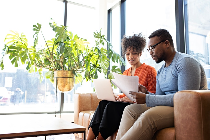 African ethnicity couple sitting on the couch, reviewing Investment Options