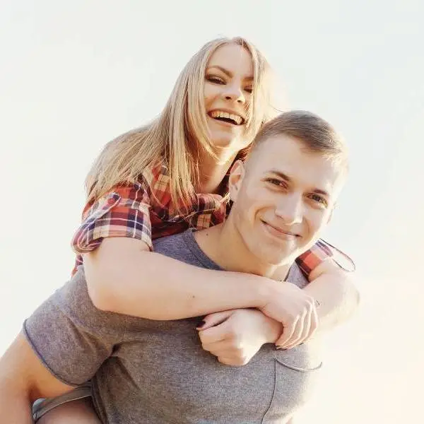 Woman on back of a man smiling in San Antonio, TX for Ketamine Therapy aftercare.