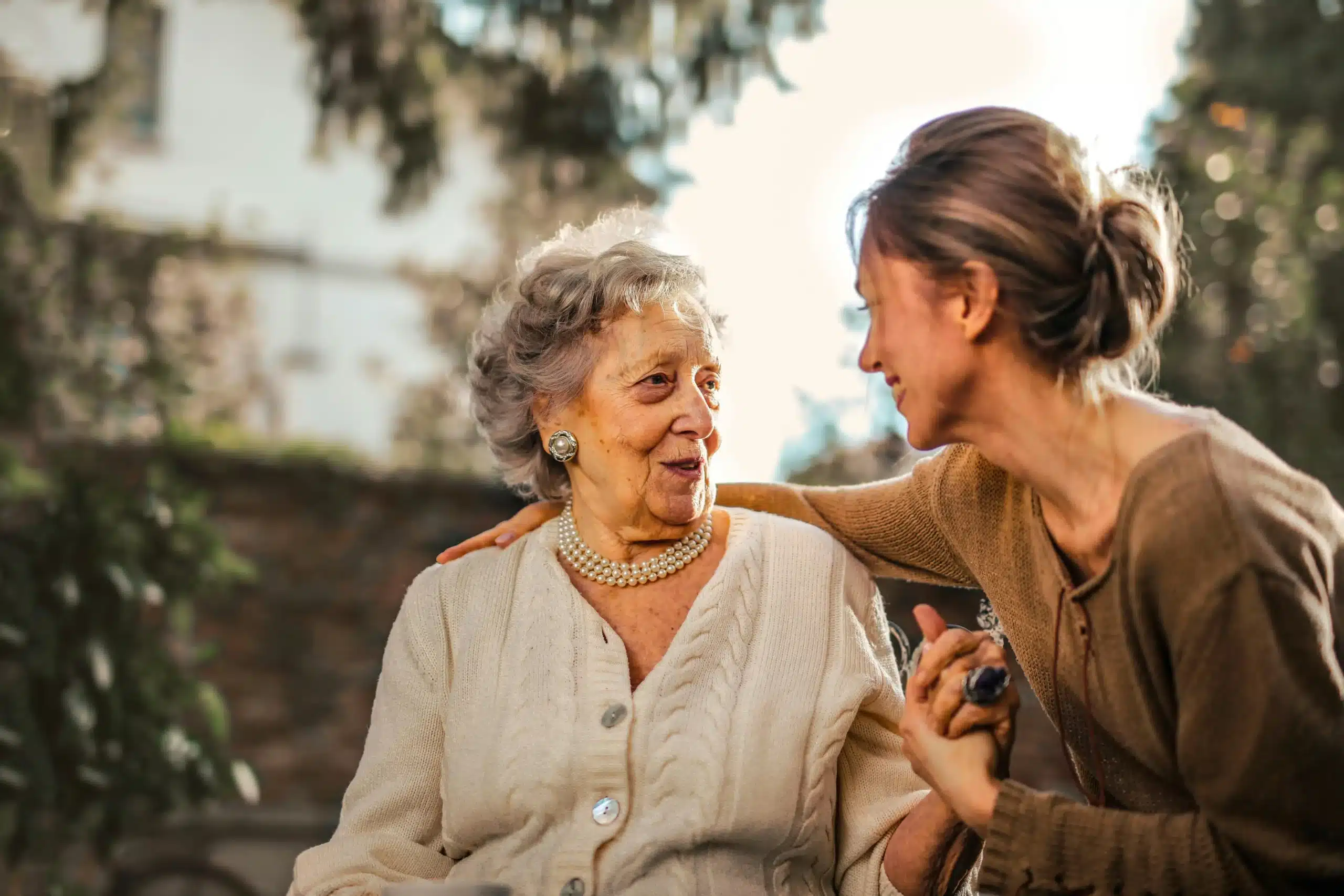 An elderly woman sits and smiles with her caregiver, representing support and the potential benefits of Ketamine for Parkinson's.